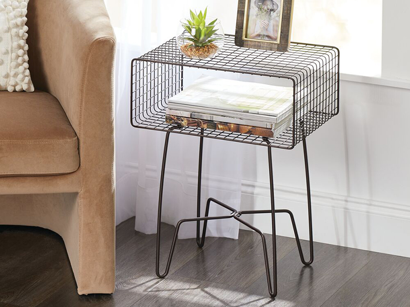 wire hairpin leg table in bronze next to brown chair with books, plant, and picture frame on table